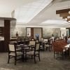 Upscale community bar and dining area with high-top seating, wood accents, pendant lighting, and residents socializing at tables.