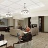 Comfortable community living room with fireplace, lounge seating, artwork, and residents relaxing and reading.