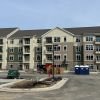 Front view of completed multi-story apartment building with balconies and construction materials in foreground.